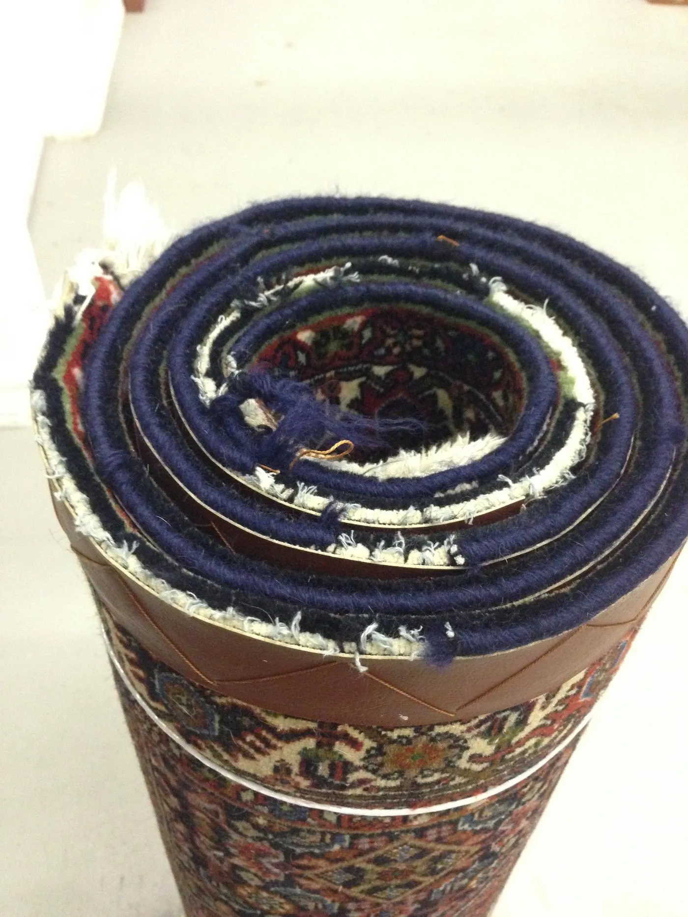 Worn, frayed edge and binding at the end of a Persian rug before hand repair